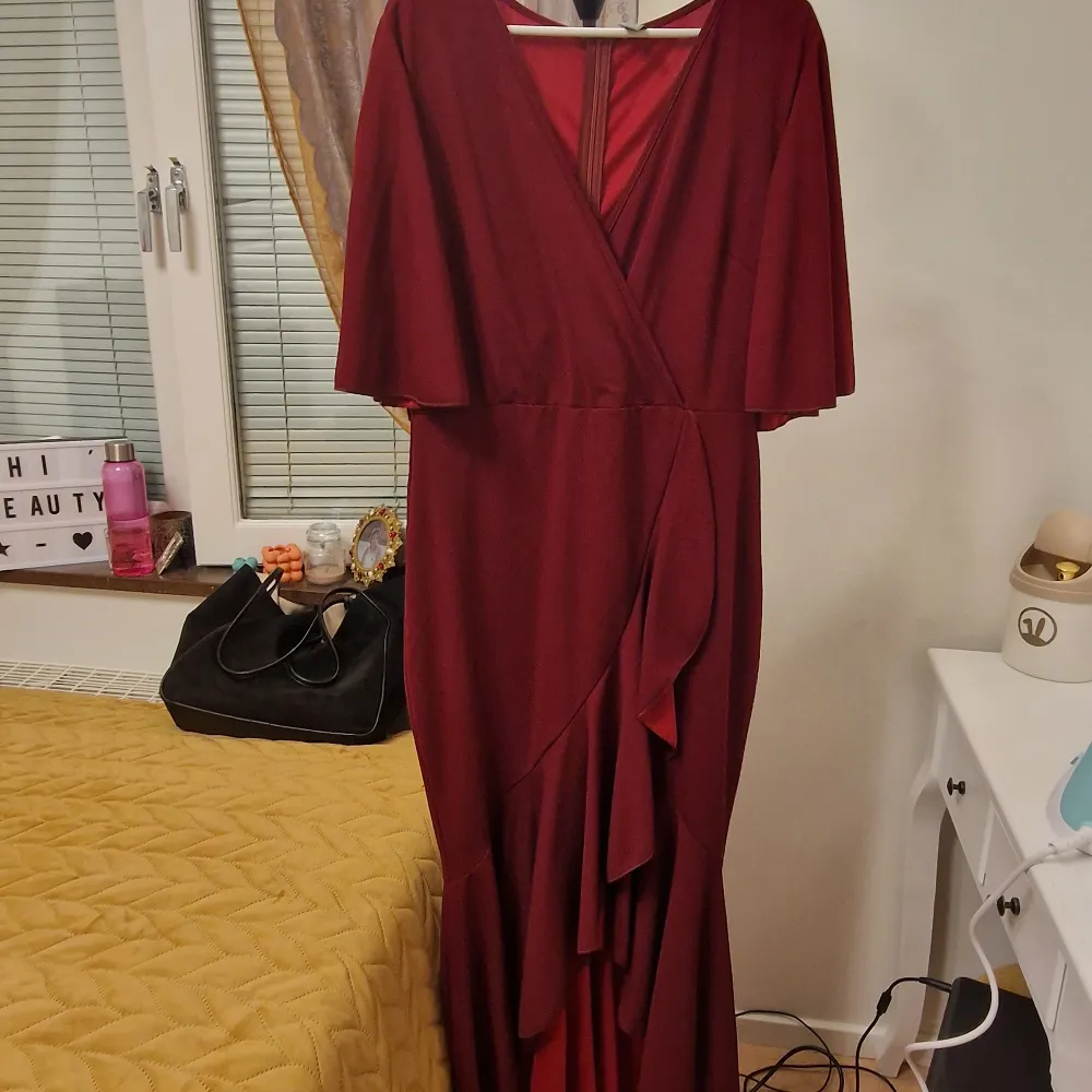 Rödvinn ruffel knälång klänning med cape axlar kort armade. Passar bra med storlek  l/xxl . Använd bara en gång för 3t bara.som nytt . Klänningar.