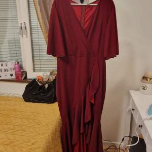 Rödvinn ruffel knälång klänning med cape axlar kort armade. Passar bra med storlek  l/xxl . Använd bara en gång för 3t bara.som nytt 