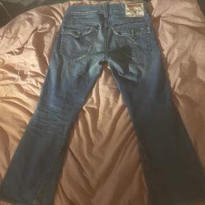 Säljer ett par snygga vintage true religion jeans med lite bootcut som tyvärr är för små för mig. Köpte dem begagnat, bra skick lite slitage vid knä och lår.  Innerben 78cm Ytterben 101cm Midja (rakt över) 45cm Pris är inte fast :)