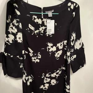 Ny satinklänning! - Ny fin satinklänning med 3/4 ärm! Marinblå med vit blommönster, knytdetaljer på ärmarna! Prislappen kvar!