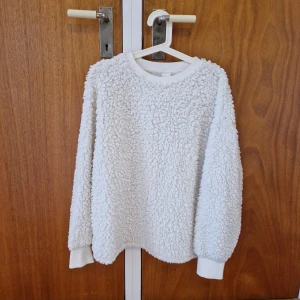 Mysig teddytröja H&M - På insidan av tröjan har det fastnat lite svarta tygnoppor annars är den i jättefint skick. Rymlig i storleken. Fluffig och riktig mysig tröja!