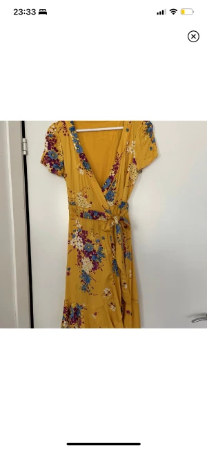 Klänning S - Snygg omlottklänning i storlek S. Knyts i midjan. Ganska urringad men snyggt skuren. Använd ett fåtal gånger och i mycket gott skick. 98% konstsilke vilket gör att det är ett väldigt mjukt och skönt material. Lite mer glans än vanlig bomull. 