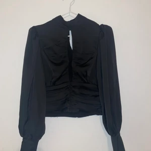 Ginatricot blus 36 - En svart blus från ginatricot i storlek 36. Finns en dragkedja på sidan och knappar i nacken och längst handlederna. Jättefin men för stor på mig så har inte kommit till användning. Aldrig använd och orginalpris är 350.