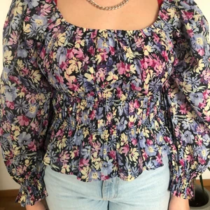 Blommig tröja från Ginatricot - Oanvänd tröja som är köpt på Ginatricot sommaren 2021. Tröjan är i storlek 46 men passar även någon som har mindre storlek. Min syster som har på sig tröjan på bilden har i vanliga fall storlek S/M, så skulle säga att tröjan passar storlek 40-44 eller M/L. Köparen står för frakten.