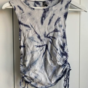 TIE DYE TOPP - Blå/vitt ribbat linne med knyte vid sidorna, går att justera högt/lågt. Väldigt bra skick. M-men tightare passform (plus stretch)