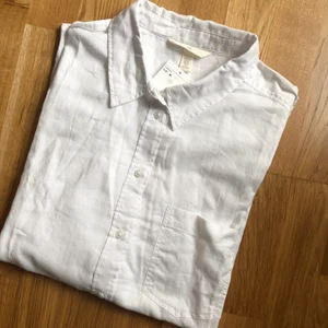 Bomullsskjorta  - Vit bomullsskjorta med krage, knäppning framtill och extra långa ärmar. Helt ny, prislapp sitter kvar. Slutsåld online. Finns vid Älvsjö torg att hämta. Kan mötas upp centrala Sthlm eller skicka via Postnord mot en fraktkostnad. 