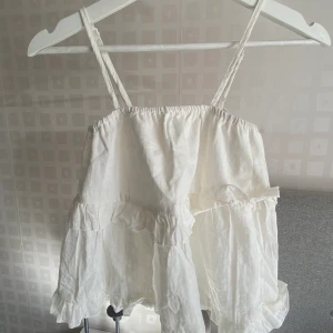 Vit söt volangotopp Xs - Säljer en vit söt liten volangtopp i Xs. Den är aldrig använd💞