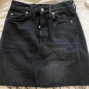 Jeanskjol - Svart slitet tvättad jeanskjol från HM, knäpps med knappar fram, bara den översta syns när den är knäppt. 