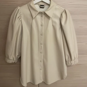 Skjorta i skinn - Beige skjorta i skinnimitation från Gina Tricot. 3/4 ärmar.