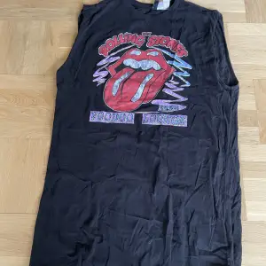 En svart Rolling Stones klänning från H&M. Den är bredaxlad, armhålen är 28cm i diameter och från armhåla till slutet är den 54cm. Använd en gång, nytt skick. Trycket är lite speciellt; det blir mer slitet för varje tvätt.