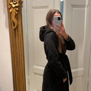 Kappa svart  - Svart kappa med knyte i midjan och även luva! Storlek 44 men har använts av mig som har 36/38 då den var tight i armarna och ryggen i storleken. Polyester och ull. Hel och ren och sparsamt använd.