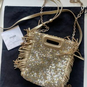 Maje mini bag gold - Säljer min limitet edition modell av ”Maje mini bag” i guldpaljetter. Köpt i Paris för cirka 2300kr och är i relativt bra skick men har defekter på insidan. Man får med kvitto, dustbag och även en guldkedja från maje som går att ta av och på!! 💕💕💕