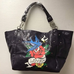 Handväska  - Mörk lila LOVE tryck  Vackra äldelstenar i formar CZ diamanter . Mycket välgjord väska i skinnimita  Mått 45*24*19cm  Totalt 6 fickor, en huvud fack samt 4 överila fickor, en huvud blixtlås fack , 