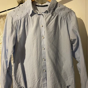 Skjorta med pärlor  - Blus/skjorta med pärlor i storlek S från zara. Nyskick. Nytvättad behöver strykas. Ljusblå.