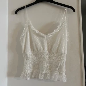 Nyskick! - En söt liten topp med spetsdetaljer och ett brett resår i midjan. Stretchig. Storlek S 30kr