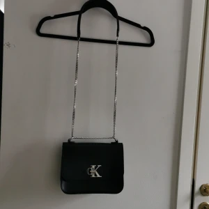 Axelremsväska Calvin Klein  - Axelremsväska från Calvin Klein  Väl använd och har några sprickor i lädret på insidan samt att loggan är nött. Men är fullt användbar!  