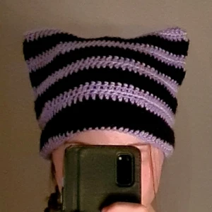 Cat beanie  - Virkad cat beanie i ljuslila och svart. Gjord i 100% akrylgarn och passar de flesta. Tveka inte att höra av dig vid frågor🫶