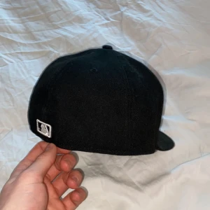 MLB NY Yankees  - Denna keps är perfekt för dig som har lite street style eller y2k. Kepsen är svart med vita tryck i onesize