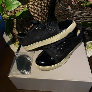 Lanvin Patent Cap Toe Sneaker Black - Hej, säljer ett par svarta Lanvin Cap Toe sneakers. De är använda men fortfarande i bra skick och lätta att fixa. Har dustbag samt extra snören från köp. Nypris runt 4000kr. Storlek 8 och passar 42/43. Priset är inte hugget i sten. Hör av dig vid frågor!