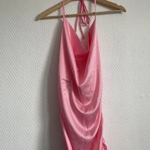 Rosa klänning  - Rosa halterneck klänning som man även kan dra åt på sidorna, i ett ”silkes” material Super fin klänning fick den av än vän men den passa tyvärr inte mig 