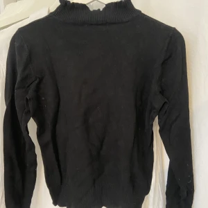 Svart poli - Svart polo med fina detaljer vid arm och hals