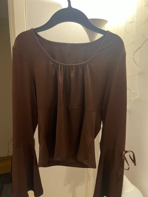 Topp - Brun topp med knytbara rosetter på ärmarna.