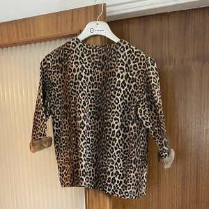 Dress i leopardmönster - Tvådelad dress med topp och kjol i fint material och fale fur vid ärmsluten