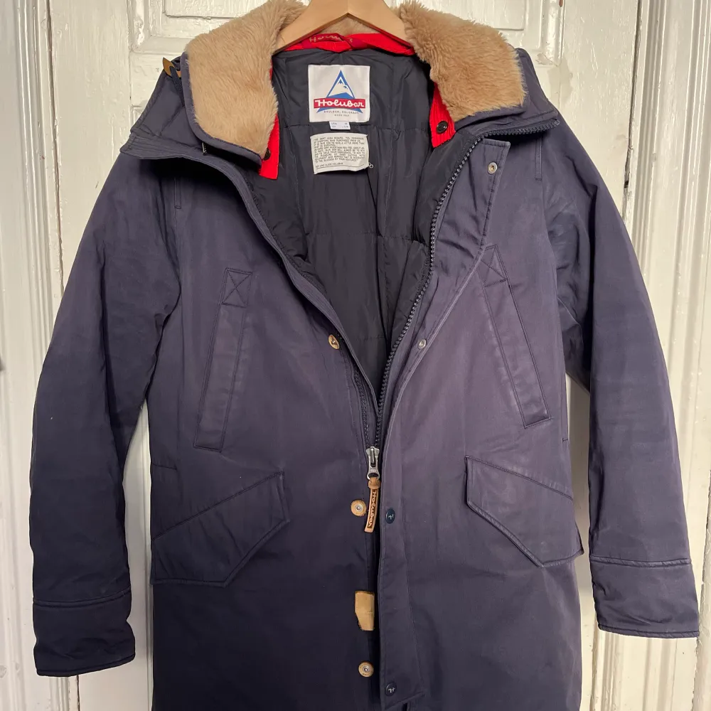 Holubar Alcan Long Parka Alcan long parka made of navy blue cotton laminate, it is a snow, rain and wind resistant fabric. This regular cut model has a double alpaca hood, removable with press studs on the front of the hood. Super warm. Super cozy. . Jackor.
