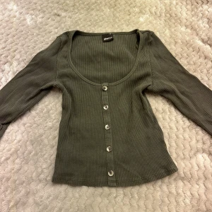 Tröja - En grön croppad tröja med knappr och långa ärmar från gina tricot. Storlek xs.  Skriv för fler bilder. 