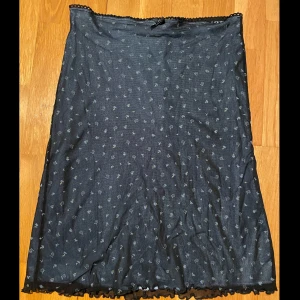 Sommar Kjol - Fin skjol med blom-print. Den har blå tyg under det tunna svarta tyget, som har blåa blommor på sig. Fin rosett och lire spets på midjan. Köpt secondhand. Skriv för mer info/bilder. Om du vill köpa skriv privat🫶