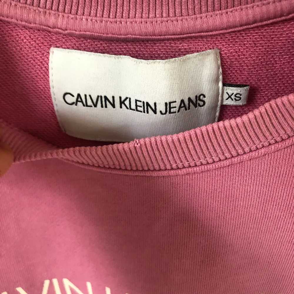En rosa Calvin Klein tröja! Det är tre små hål på ena ärmen som ni ser i bild 3! Annars fint skick! Storlek Xs men ganska liten! Frakten är 66kr så 200+66=266kr! . Tröjor & Koftor.