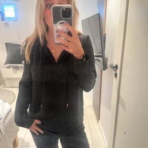 svart siden blus  - Svart siden blus, okänt märke, kan knytas fram, med guldiga detaljer längst ut p snörena! 