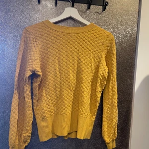 Senapsgul tröja - Tröjan är mindre skrikfärgad i verkligheten, har en fläck längst ner som borde gå bort i tvätten, tröjan är annars i fint skick och skönt material