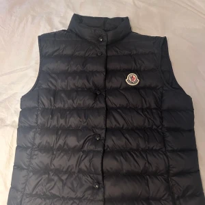 Moncler vest - Säljer min moncler vest, modellen är liane gilet. Skicket är perfekt då den endast är använd Max 3 gånger samt tvättad 0. Skicket är 10/10 då det inte ens finns en repa. Säljer denna väst för den endast blir liggandes i garderoben. 