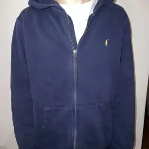 En marinblå ralph lauren hoodie med guldiga detaljer Storlek: XL(kids) Material: Blanding mellan Polyester och Bomull