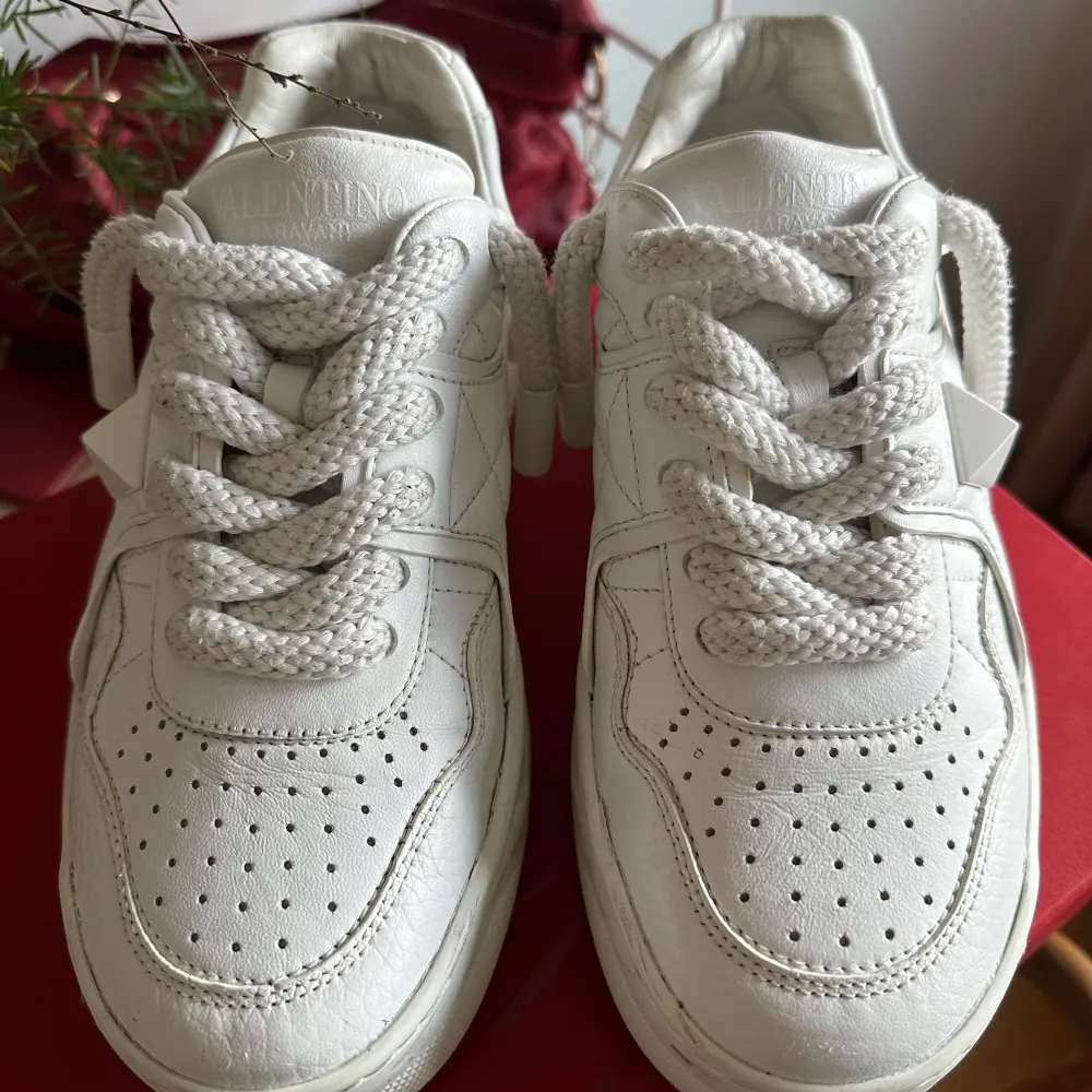 Vita valentino sneakers. Skorna är använda men fortfarande i bra skick, defekter visas tydligare i DM. Orginalförpackning, dustbag, och äkthetsbevis medföljer. Kvitto finns. Nypris 8700kr men jag säljer för 3000.. Skor.