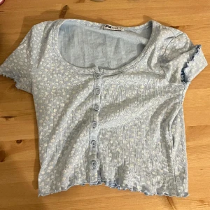 Ljusblå t-shirt - Jättefin ljusblå t-shirt med vita blommor på. 