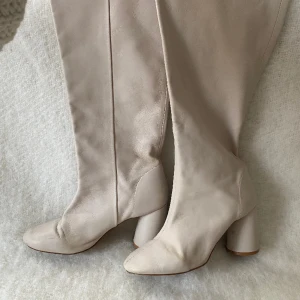 Höga stövlar från Other stories - Höga beiga stövlar i stolek 39 från Other stories. Lite repor och färgskiftningar finns, därav det låga priset trots att de kostade närmare 3000kr nya. 