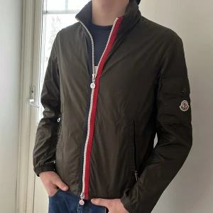 Moncler windbreaker - Sjukt fet moncler windbreaker som är Perfekt till våren! Skick 9,7 nästan ny, tillkommer moncler påse, kvitto och tags vid köp, nypris 5600, Modell ca 1,80. Finns en luva i nacken som går och fälla ut🤩