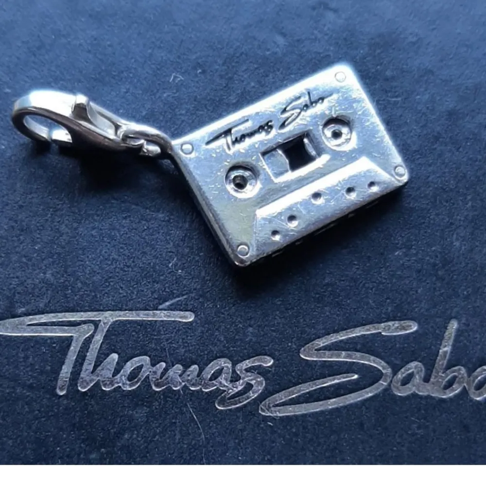 Thomas Sabo berlock, fräckt kassettband i fint begagnat skick.  Ask/påse ingår ej.  Kolla bilder o ställ ev frågor före bud.  Frakt tillkommer. . Accessoarer.