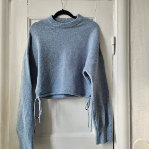 Stickad tröja - Blå stickad tröja med snören som kan dras åt i midjan. 
