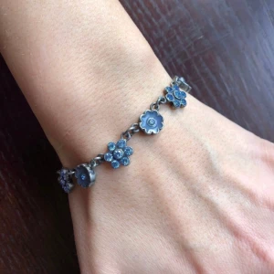 Vackert blommigt armband - Vackert armband med blå blommor i olika utföranden. Somrigt och fint! Levereras i smyckespåse. Mkt fint skick!