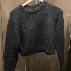 Blå stickad tröja från Zara - En blå stickad tröja från Zara med långa ärmar och en ribbad rund halsringning. Tröjan har en croppad passform och är tillverkad i ett mjukt och bekvämt material.