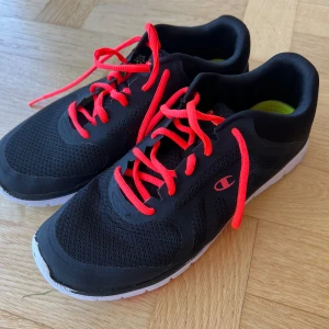 Sportskor champion storlek 41 - Svarta sportskor med orangea detaljer från champion. Använda ett fåtal gånger inomhus.