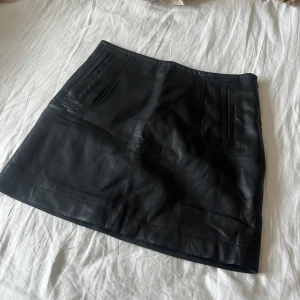 Kjol - Imitations- läderkjol med fickor. Mycket skön! Bra skick, köpt second hand i Ungern.