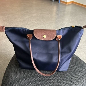 Longchamp liknande väska - Superfin väska som liknar longchamp. Den går att vika så den tar väldigt liten plats. Den är lika stor som en Longchamp medium. Kommer inte till någon användning.