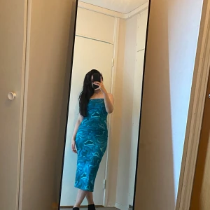 Sommrig klänning  - En blå kläningen med olika nyanser av blå. Passar perfekt till sommaren, har en liten öppen rygg och en öppning i slutet. 