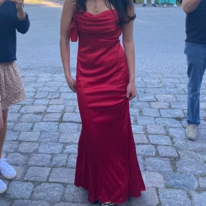 Balklänning i satin❤️ - Säljer denna drömmiga balklänning i röd satin från NLY. Endast använd en gång och går nedanför fötterna på mig som är 169 cm. Den har en så fin passform, med en djup rygg och lite eftersläp som gör den till den perfekta balklänningen. 