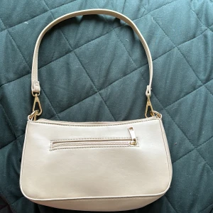 Beige axelremsväska med guld detaljer  - Beige väska med guld detaljer  Ca 25 x 15 cm  Innerfack och ytterfack   Avtagbar rämm, Nyskick   Nypris: 300 kr  Pris kan diskuteras 💕