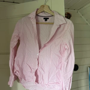 Skjorta Tommy Hilfiger  - Ljusrosa skjorta med vita ränder från Tommy Hilfiger, knappt använd. USA storlek (L 12/14 years) men skulle säga det är S💕ostruken på bilden  Köparen står för frakten💕 90kr